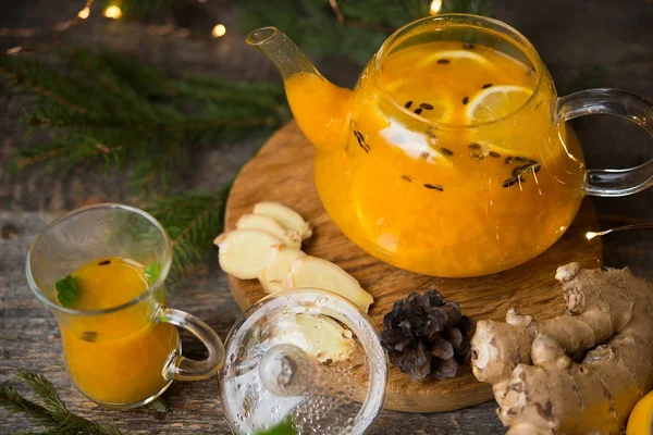 Hot winter drink of sea buckthorn with spices, served with Christmas decorations and garlands. Selective focus.