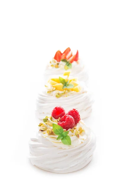 Individual cake dessert Anna Pavlova with berries and cream on a white background