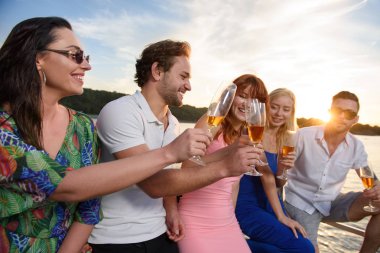 Arkadaşları şampanya içmek ve eğlenmek yatta günbatımı sırasında