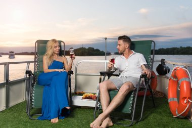 Sevgi dolu bir çift bir yatta içecekler şarap, gün batımını karşılar ve büyük bir zaman var