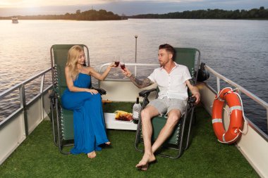 Sevgi dolu bir çift bir yatta içecekler şarap, gün batımını karşılar ve büyük bir zaman var