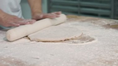 Aşçı dışarı hamur rulo. O ünlü restraunt çalışıyor. O beyaz çalışma Süiti giyer.