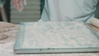Aşçı hamur fırın tepsisine bırakır. O ünlü restraunt çalışıyor. O beyaz çalışma Süiti giyer.