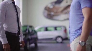 Satıcı ve istemci el sıkışın. Satıcı anahtarları arabada istemciye verir.