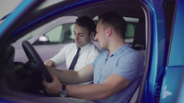 セールスマンは クライアントのためのタブレットの車の仕様を示しています 彼らは車の中で座っています 車は青 それはブランドの新しい — ストック動画