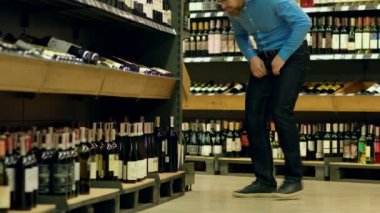 Sommelier şarap bir şişe içki dükkanında seçer.