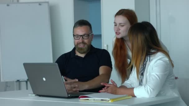 同事们在办公室 有胡子和眼镜的中年男子坐在办公室的笔记本电脑两名同事讨论草案 — 图库视频影像