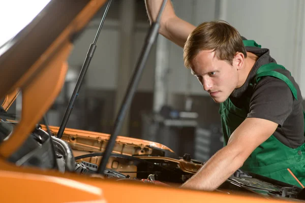 Joven Mecánico Con Mono Verde Está Reparando Motor Automático Mientras —  Fotos de Stock