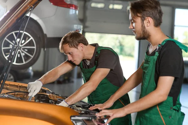 Dois Jovens Mecânicos Macacão Verde Tentam Consertar Motor Carro Laranja — Fotografia de Stock