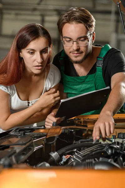 Young Mechanic Shows Cause Malfunction Orange Car Girl Client — Stock Photo, Image