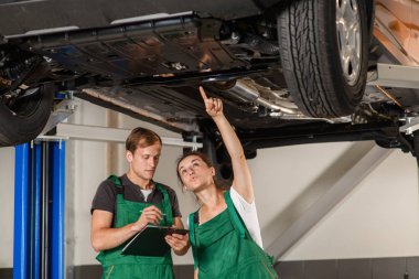 Bir güzel ve Genç kız Çilingir araba bakım merkezi'onun meslektaşı ile tanılama aracın süspansiyon yapar, onlar yeşil tulum giymiş