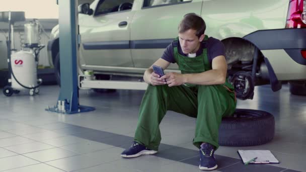 Der Mechaniker Sitzt Steuer Des Autos Und Liest Etwas Telefon — Stockvideo