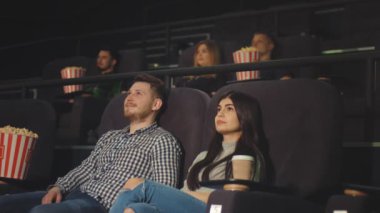 Bir arkadaşıyla bir film sinemada izlerken gülen ve ekranda gördükleri genç bir adam