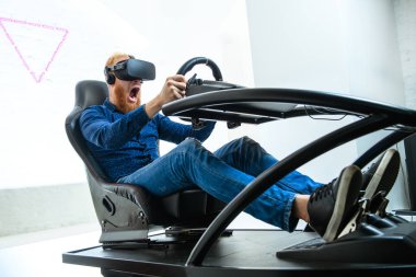 Bir genç, yakışıklı, bir mavi spor kıyafeti giyen, Yarış, bir sanal gerçeklik simülatörü çalış