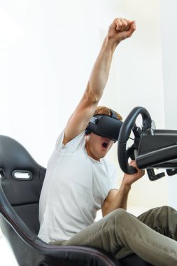 Bir yarışta, bir sanal gerçeklik simülatörü oynayan beyaz tişört, bir genç, yakışıklı adam
