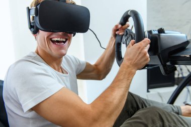 Bir yarışta, bir sanal gerçeklik simülatörü oynayan beyaz tişört, bir genç, yakışıklı adam