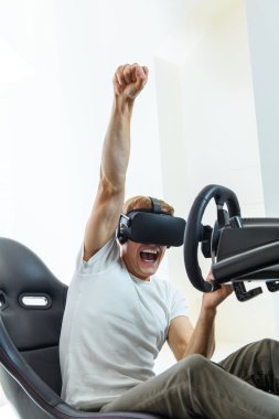 Bir yarışta, bir sanal gerçeklik simülatörü oynayan beyaz tişört, bir genç, yakışıklı adam