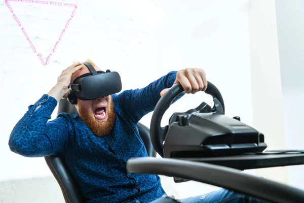 A young, handsome guy, in a blue sports suit, plays in the race, on a simulator of virtual reality