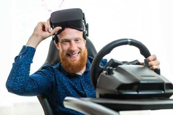 A young, handsome guy, in a blue sports suit, plays in the race, on a simulator of virtual reality