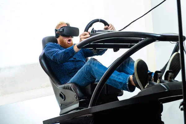 A young, handsome guy, in a blue sports suit, plays in the race, on a simulator of virtual reality
