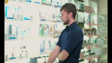 Genç adam eczane ilaç seçer, sonra da aşağı sinirli görünüyor.