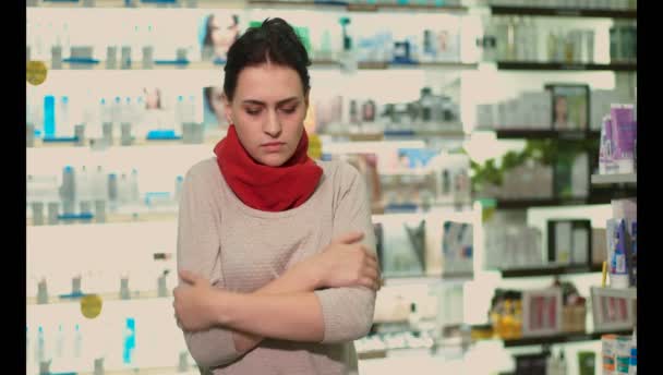 一个冷的女孩站在药店里 喉咙痛 脖子被红领巾包裹着 — 图库视频影像