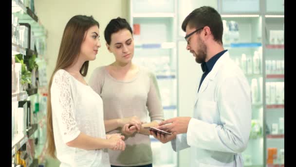 Joven Farmacéutico Muestra Dos Clientes Farmacia Disponibilidad Medicamentos Interés — Vídeo de stock