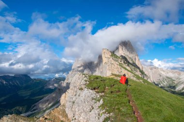 Odle - Geisler grup doğal görünümü. Ön plan üzerinde kırmızı ceketli bir oturma turist bul. Milli Parkı Puez Odle, Val Gardena, Dolomites, South Tyrol, İtalya