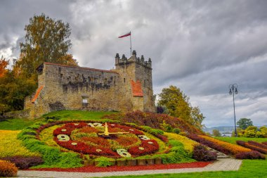 Picturesque view to former royal castle in Nowy Sacz, Poland at autumn day. Colorful flower clock on foreground clipart