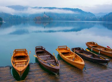 Sis om arka plan Slovenya kaplı dağları ile Lake Bled rıhtımda demirleyen tekneleri ile sonbahar sahne