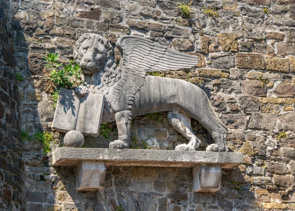 Winged Lion of Saint Mark on the wall of historic Castle in Gorizia, Italy. Lion of Saint Mark is the symbol of medieval Republic of Venice. Latin inscription \'Peace to You, Mark Evangelist\'