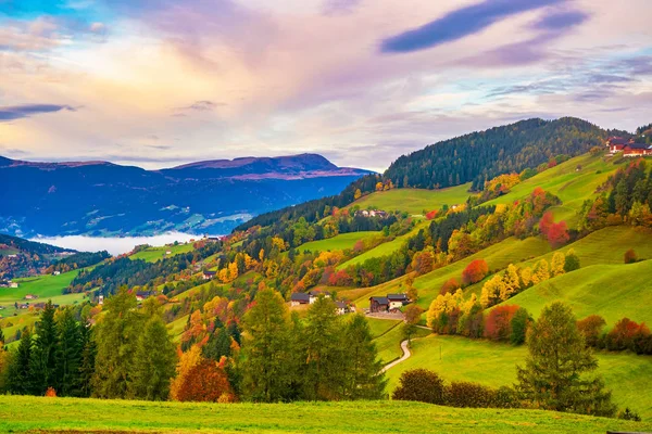 Pintoresco paisaje otoñal con prados, árboles de follaje y colinas de montaña bajo nubes de colores — Foto de Stock
