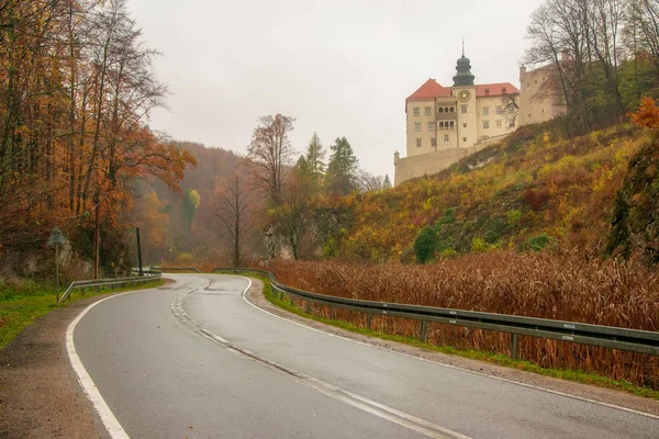 Paisagem de outono de estrada sinuosa, árvores coloridas e castelo de Skala Pieskowa no Parque Nacional de Ojcow, Polônia — Fotografia de Stock