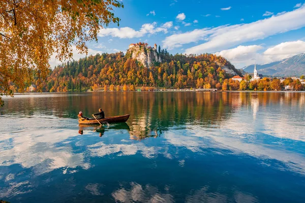 Autumn scenery on Bled lake, Slovenia. Romantic couple sailing by boat — Stock Photo, Image
