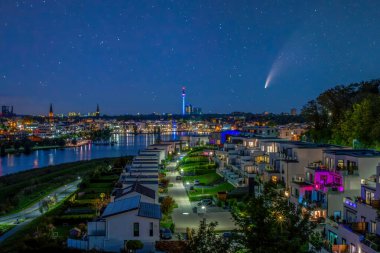 C 2020 F3 Neowise kuyruklu yıldızı Dortmund, Almanya 'da Phoenix Gölü üzerinde gece gökyüzünde. Şehir silüeti ve Florian Kulesi alacakaranlıkta aydınlandı
