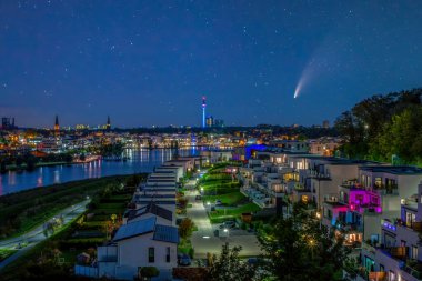 C 2020 F3 Neowise kuyruklu yıldızı Dortmund, Almanya 'da Phoenix Gölü üzerinde gece gökyüzünde. Şehir silüeti ve Florian Kulesi alacakaranlıkta aydınlandı