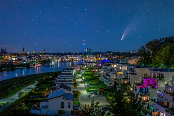C 2020 F3 Neowise kuyruklu yıldızı Dortmund, Almanya 'da Phoenix Gölü üzerinde gece gökyüzünde. Şehir silüeti ve Florian Kulesi alacakaranlıkta aydınlandı