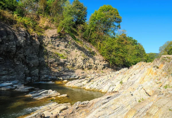 Dry rocks on river bank. Drought on the river Prut. Shallow Huk waterfall. Kosiv, Ukraine