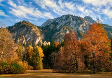 Bavyera Alpleri ve Hohenschwangau Kalesi 'nin göz kamaştırıcı manzarası. Gökyüzü resimli ve güneşli sonbahar gününde renkli ağaçlar, Almanya..