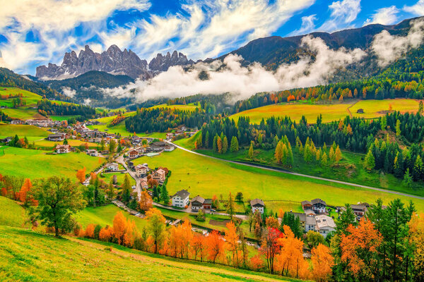 Colorful autumn scenery in Santa Maddalena village with mountain peaks on background at sunny day. Dolomite Alps, South Tyrol, Italy.