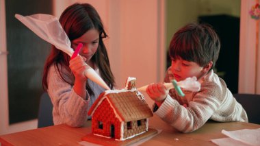 Küçük kardeş zencefilli çöreğin üstüne kraliyet buzu şekeri ekliyor.