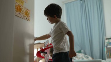 Küçük çocuk otopark oyuncağıyla yatak odasının zemininde oynuyor. Çocukluk eğlence aktivitesi