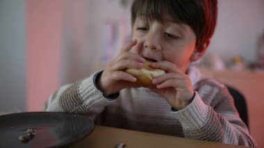 Masada oturan küçük çocuk bir ısırık ekmek, basit bir yemek, 5 yaşında çocuk karbonhidrat yiyor.