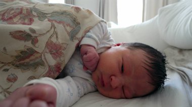 Çiçekli bir battaniyenin altında uzanan yeni doğmuş bebek, gözleri nazikçe kapalı, huzurlu ve güvenli bir çevreyi taşıyor, bebeklik, rahatlık ve yaşamın ilk aşamaları için mükemmel..