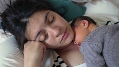 Anne ve yeni doğan bebek huzur içinde uyuyorlar, bebek göğsünde dinleniyor, huzurlu bir yuvada huzurlu ve şefkatli bir bağ ve sevgi anı yakalıyorlar..