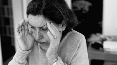 Şiddetli baş ağrısı olan yaşlı bir kadın, elleri şakaklara baskı yapıyor, derin konsantrasyon ve zihinsel gerginlik. Yaşlanan cilt ve yüz hatları, stres yoğunluğu, duygusal acı..