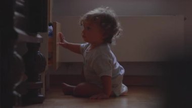 Kıvırcık saçlı çocuk pencerenin yakınına doğru küçük bir adım atarak merakla ve kararlılıkla çevreyi keşfediyor.
