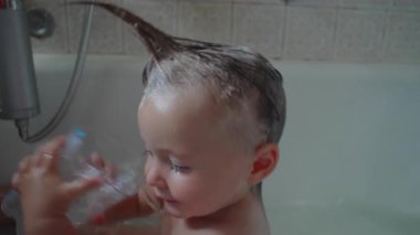 Bebek banyoda plastik konteynırdan su içerken, yaşlı kardeş stilleri ıslak saçlar neşeli punk şeklinde, kaygısız ve eğlenceli aile bağları anlarında evde.