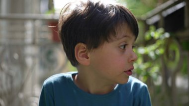 Dışarıdaki genç çocuk, tuhaf bir ifadeyle yan tarafa bakıyor, merak ve tefekkür anı. çocukluğun doğal merakı ve dikkati