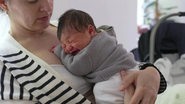 Anne, yeni doğmuş bebeğini göğsüne yakın bir yere yatırıyor, sıcaklık ve bakım yayıyor. Huzurlu bir ev ortamında anne ve çocuk arasındaki şefkat ve derin bağ